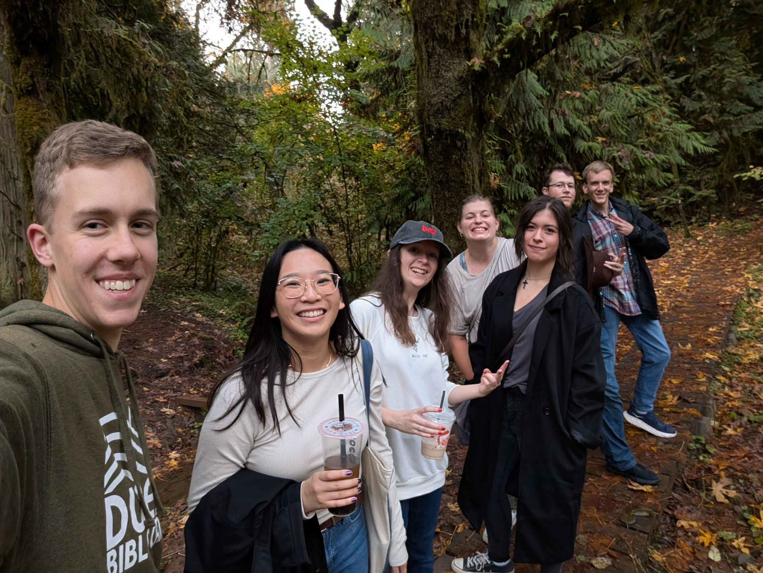 Photo of young adults in the wilderness having a great time, wearing sweaters and smiling.